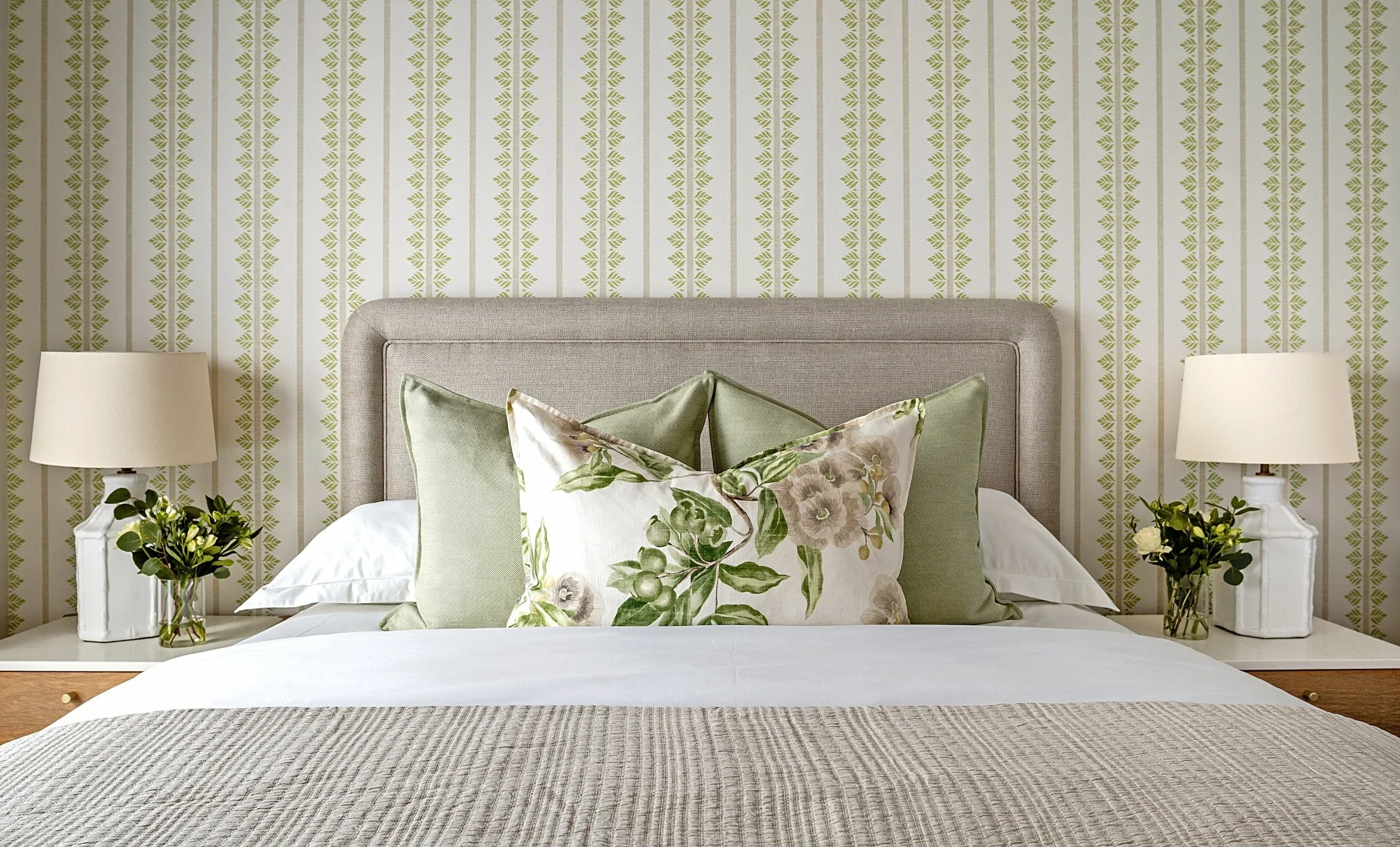 Second bedroom at The Glen, Camps Bay: green and white patterned wallpaper, a light upholstered headboard and botanical print cushions