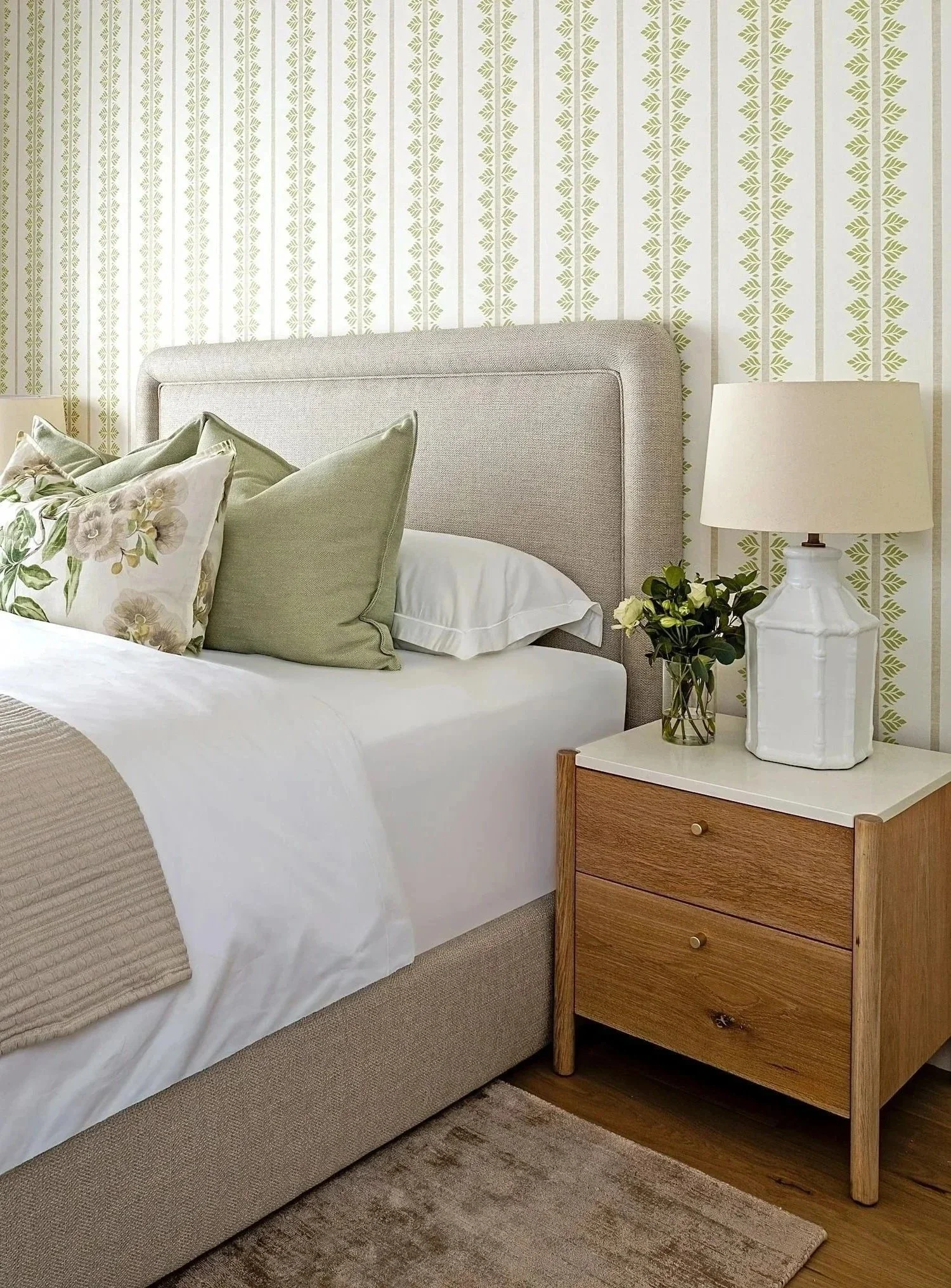 Second bedroom at The Glen, bedside detail: oak bedside, white ceramic lamp, sage cushions
