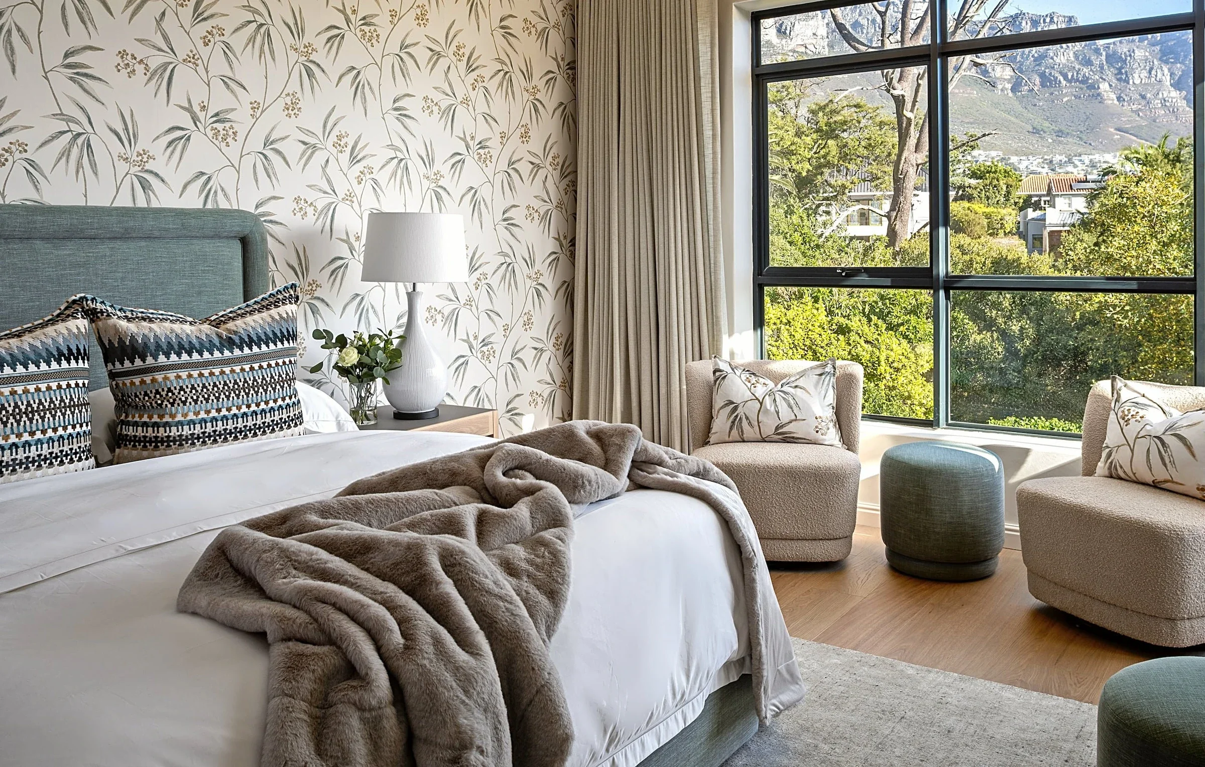 Main bedroom at The Glen, towards the window: two boucle swivel chairs, a green ottoman and the mountain