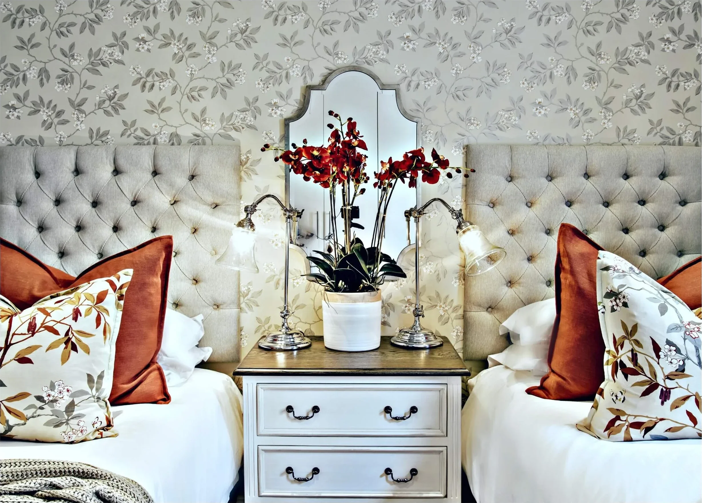 Twin bedroom in Johannesburg with buttoned headboards, rust cushions and a painted chest between the beds