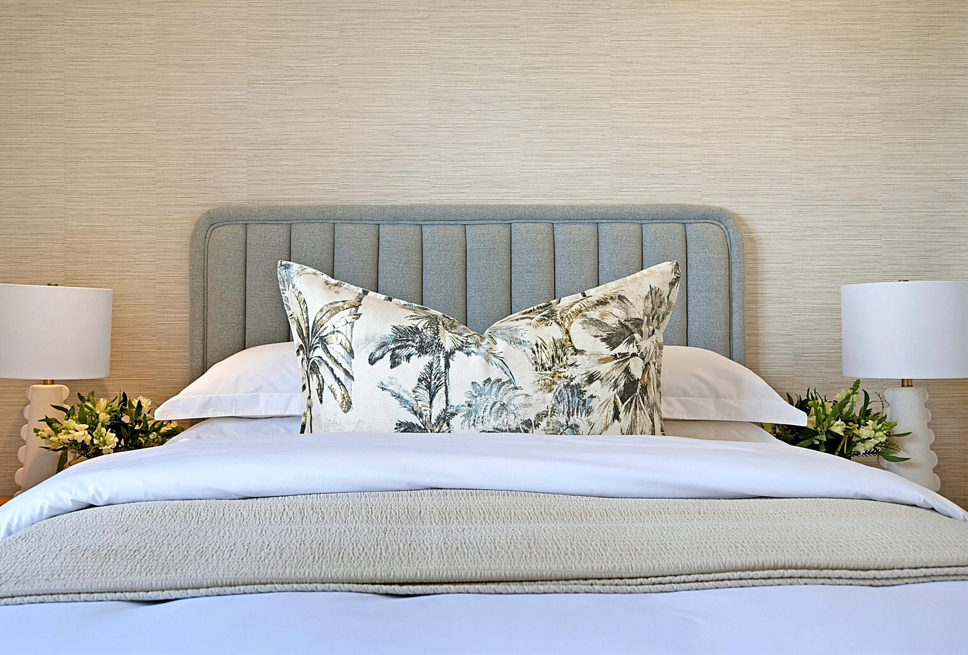 Guest bedroom at Simbithi Eco-Estate: textured wallcovering, a grey-blue channel-stitched headboard, oak bedsides, bobbin lamps and coastal prints