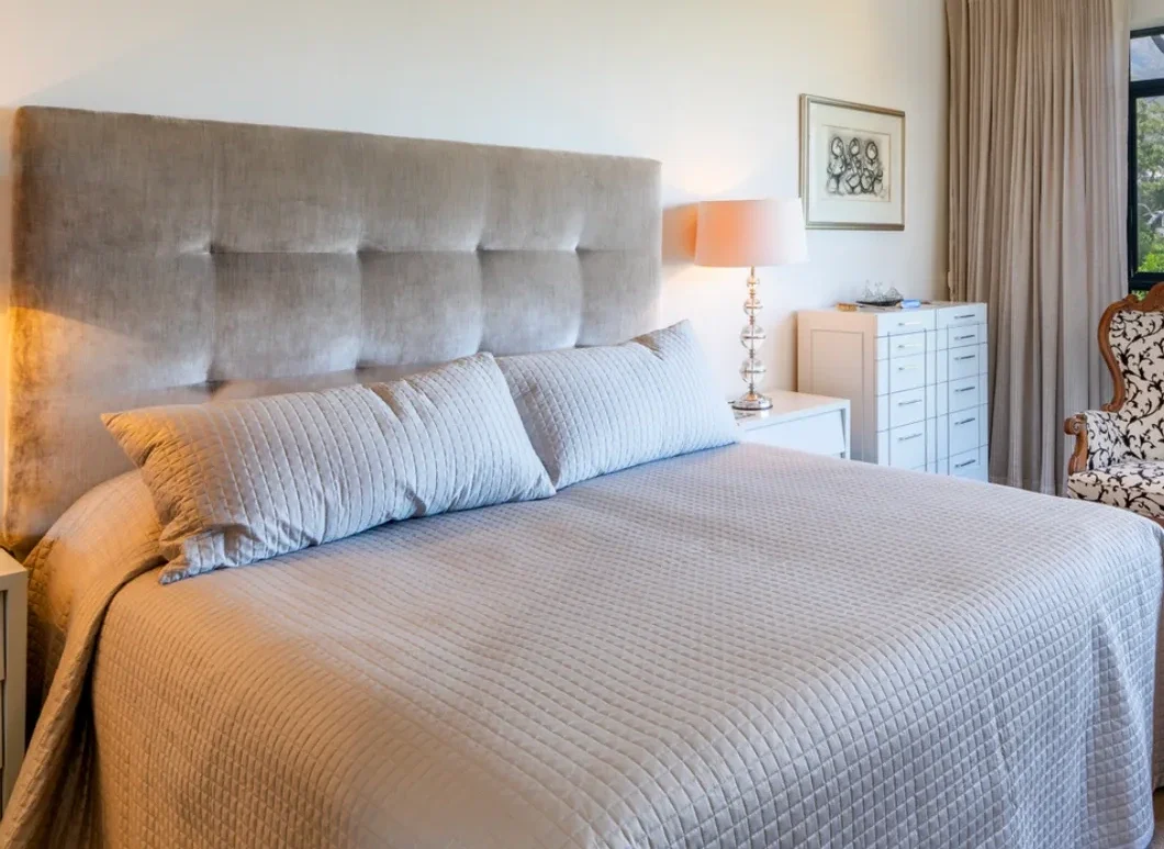 Main bedroom at The Glen before decoration: silver velvet headboard and glass-stemmed lamps
