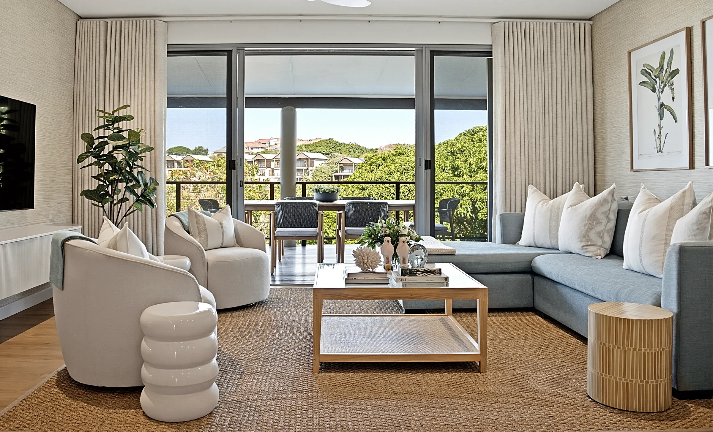 Living room at Simbithi Eco-Estate: curved cream armchairs, a grey-blue sofa and the covered terrace beyond