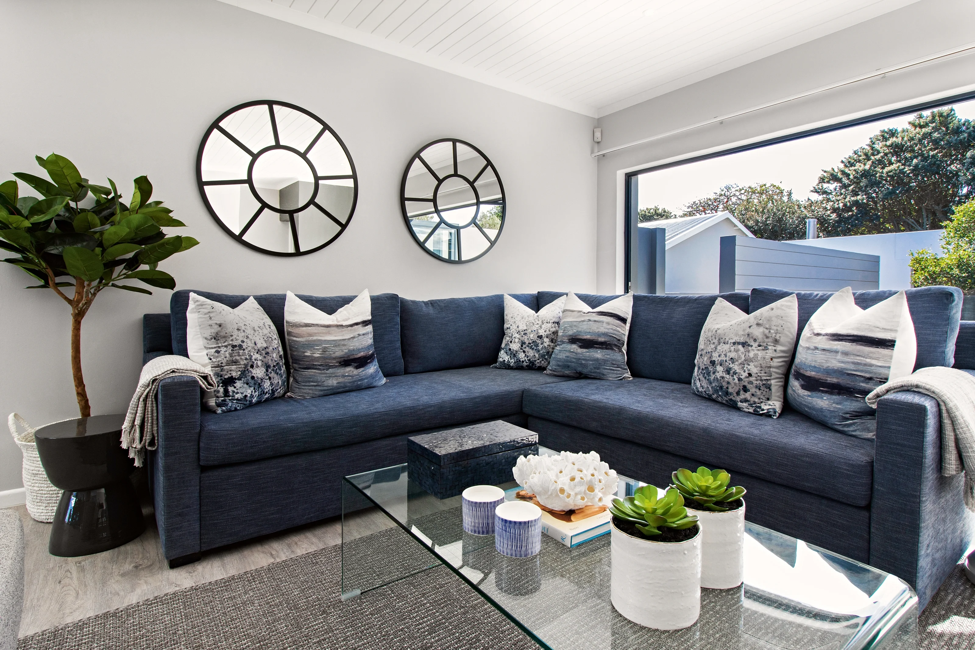Second living room at Kenton-on-Sea: navy sofa, round mirrors, patterned cushions