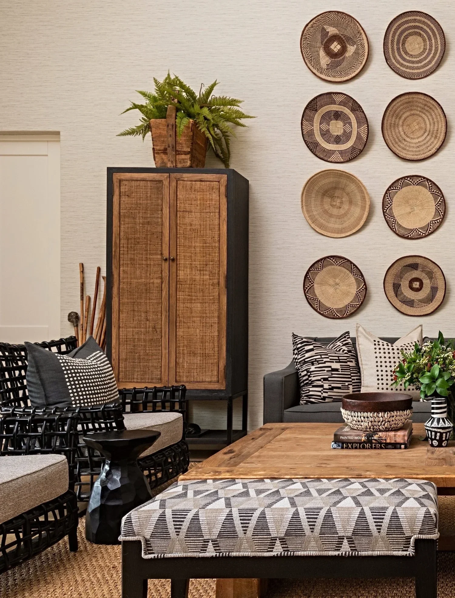 Detail at Loxley Estate: a woven basket wall above a cane cabinet with ceramics, plants and African-inspired prints